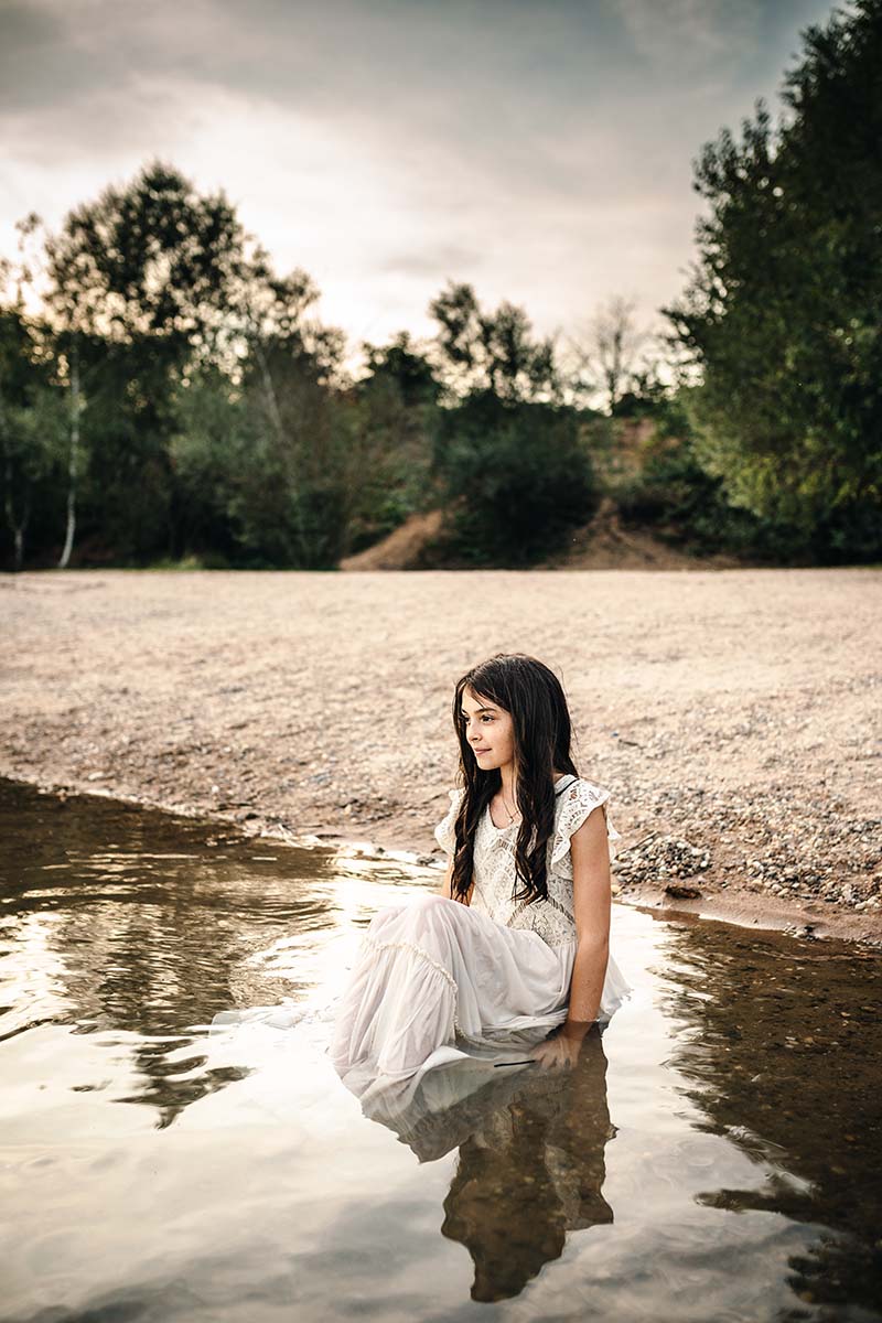 Mädchen sitzt im Wasser im weißen Kleid